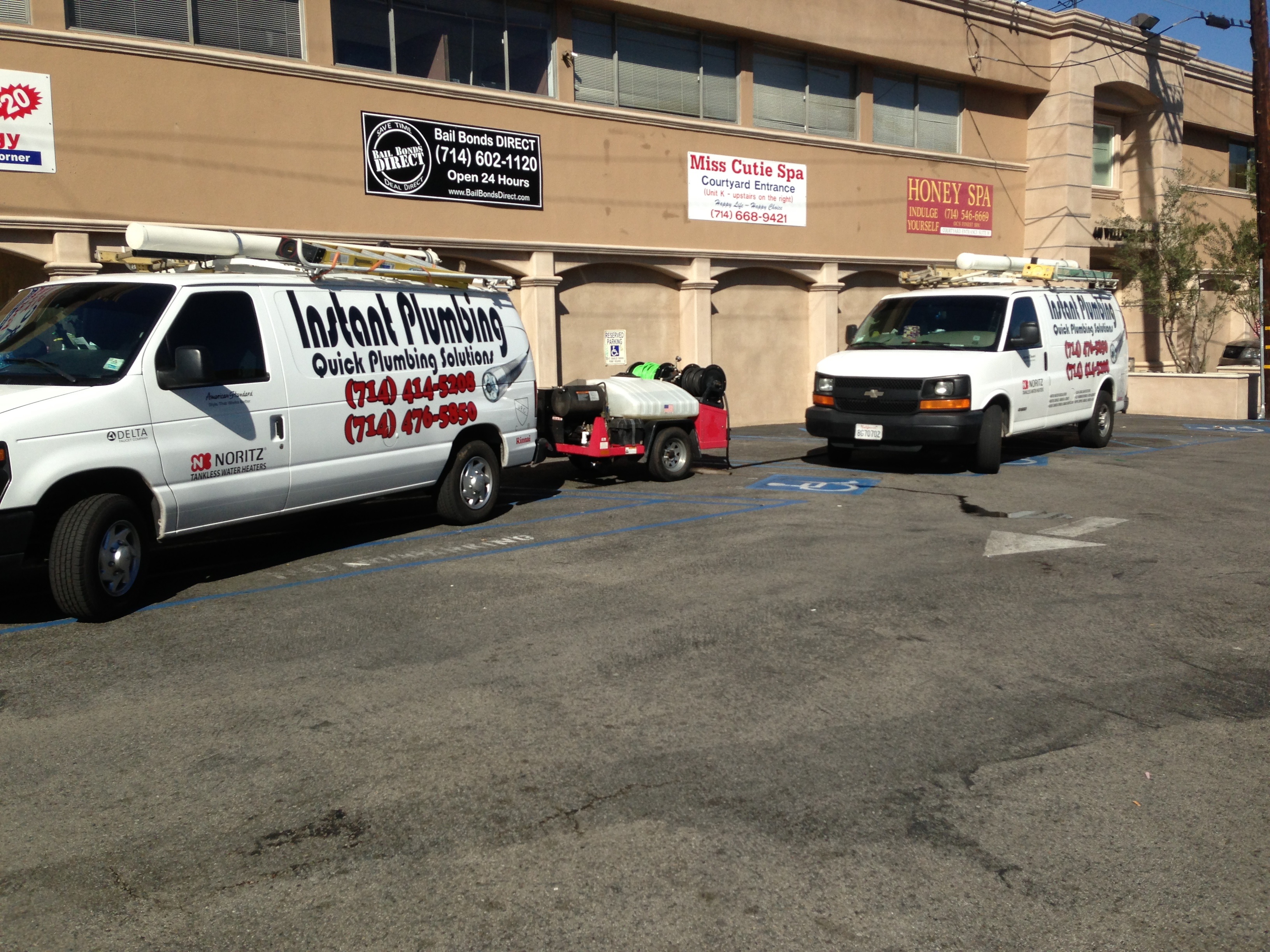 Service vans parked in lot outside commercial building with business signage