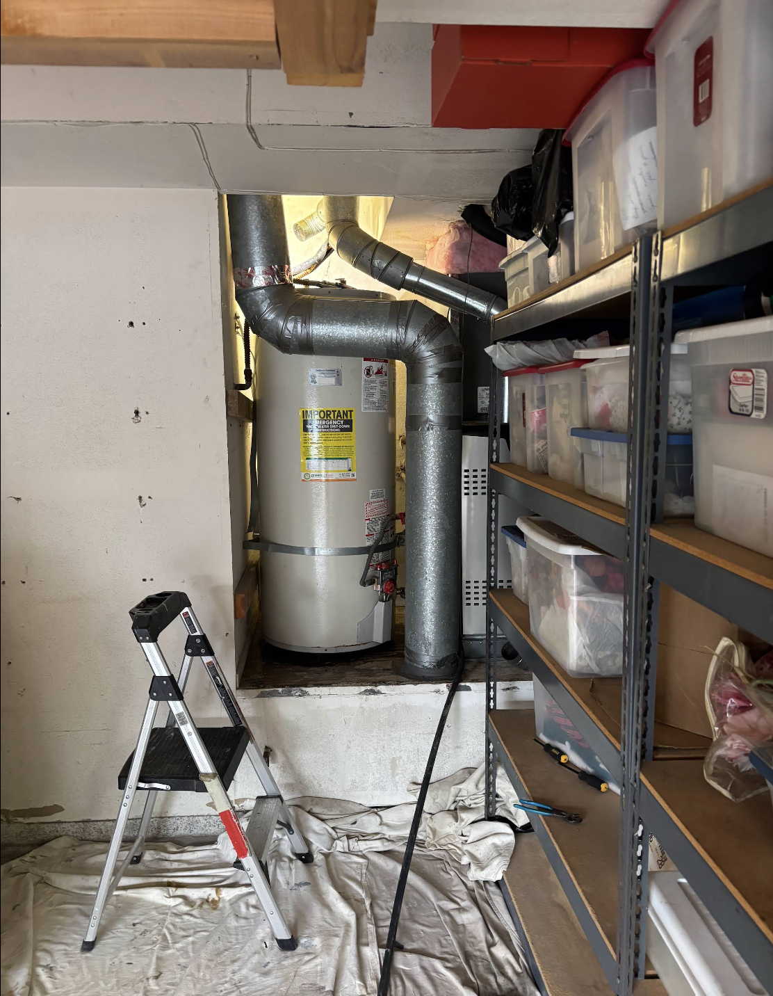 Water heater with ductwork in basement utility room next to storage shelving