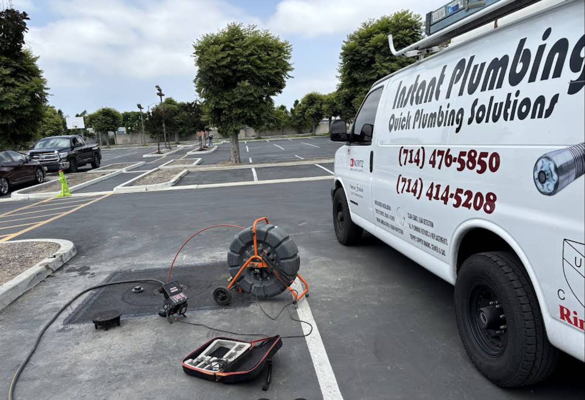 Inland Plumbing service van parked next to drain cleaning equipment on parking lot pavement